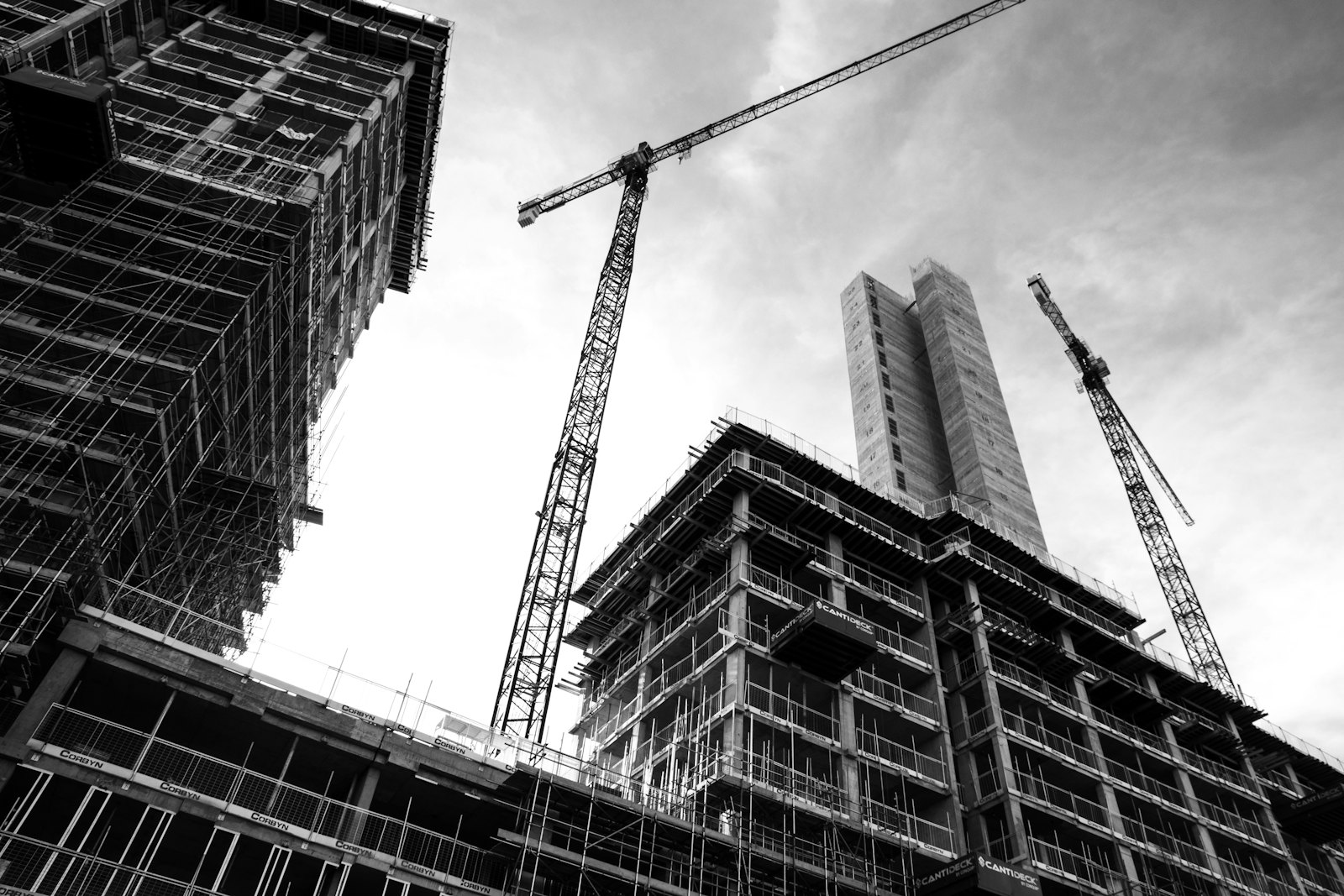 Construction crane lifting materials over a building frame on site
