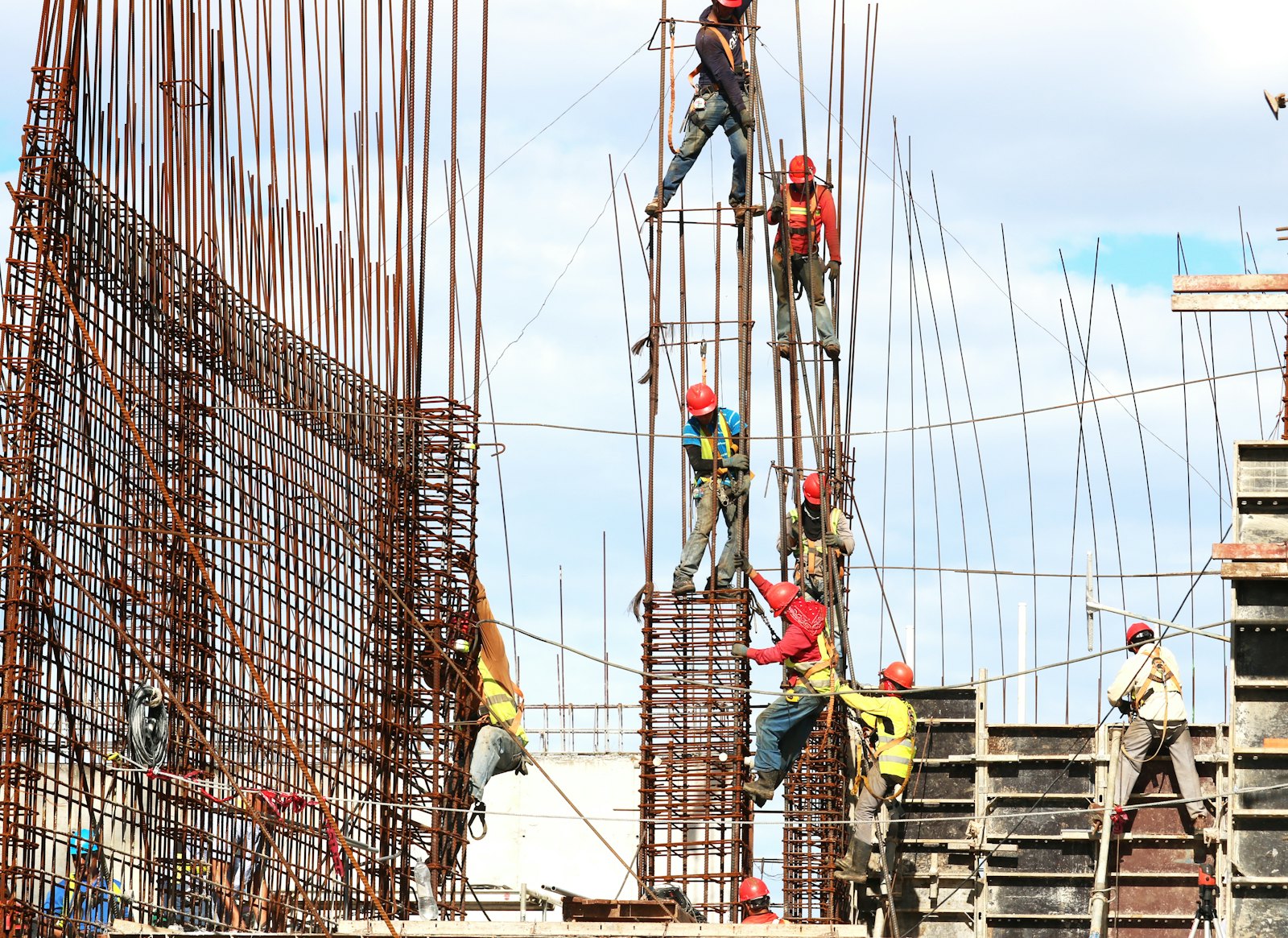 Workers tying rebar column cages on an unfinished RCC grey structure frame